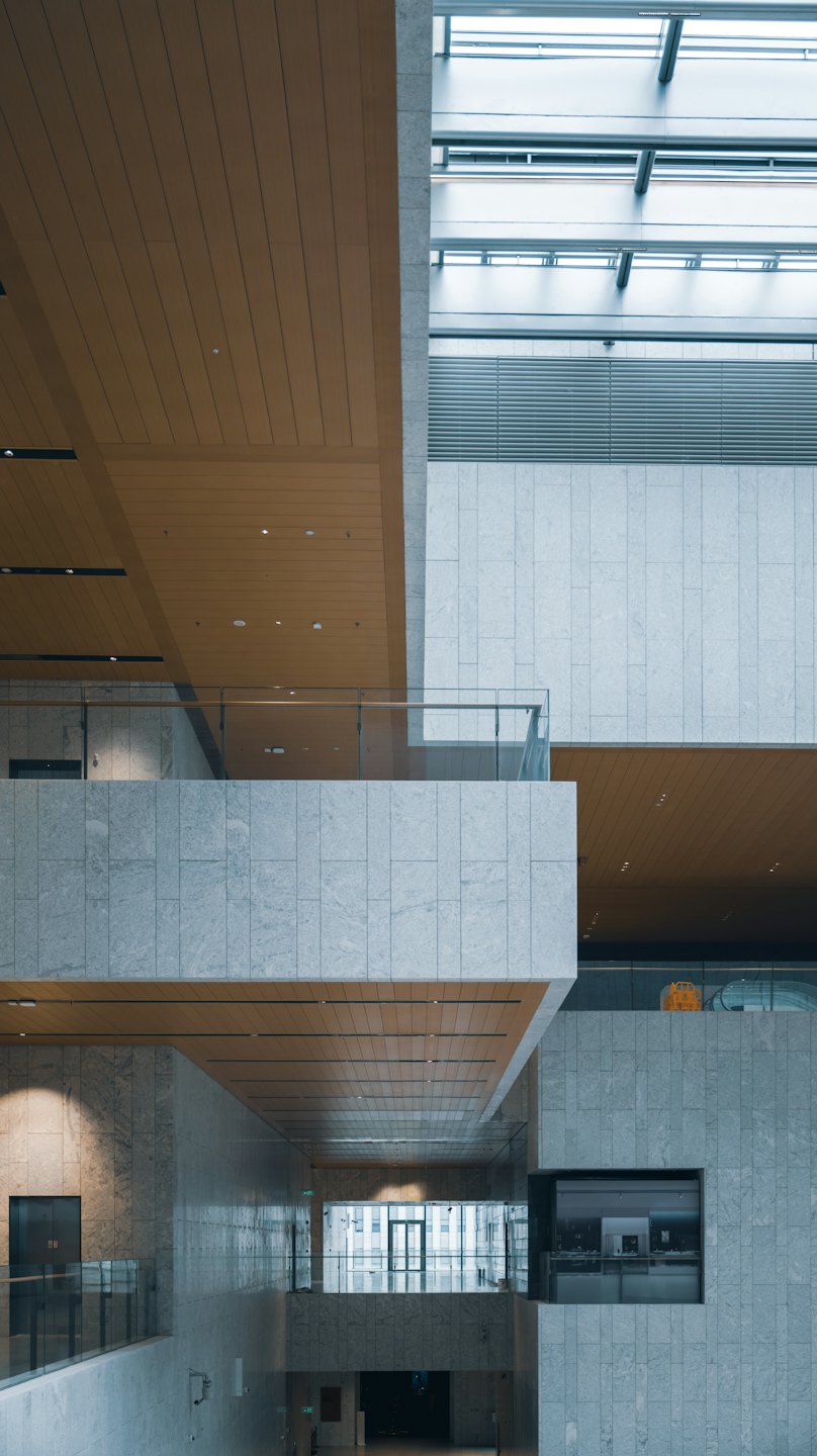 Nowoczesne atrium budynku z kamiennymi ścianami i drewnianymi panelami sufitowymi.